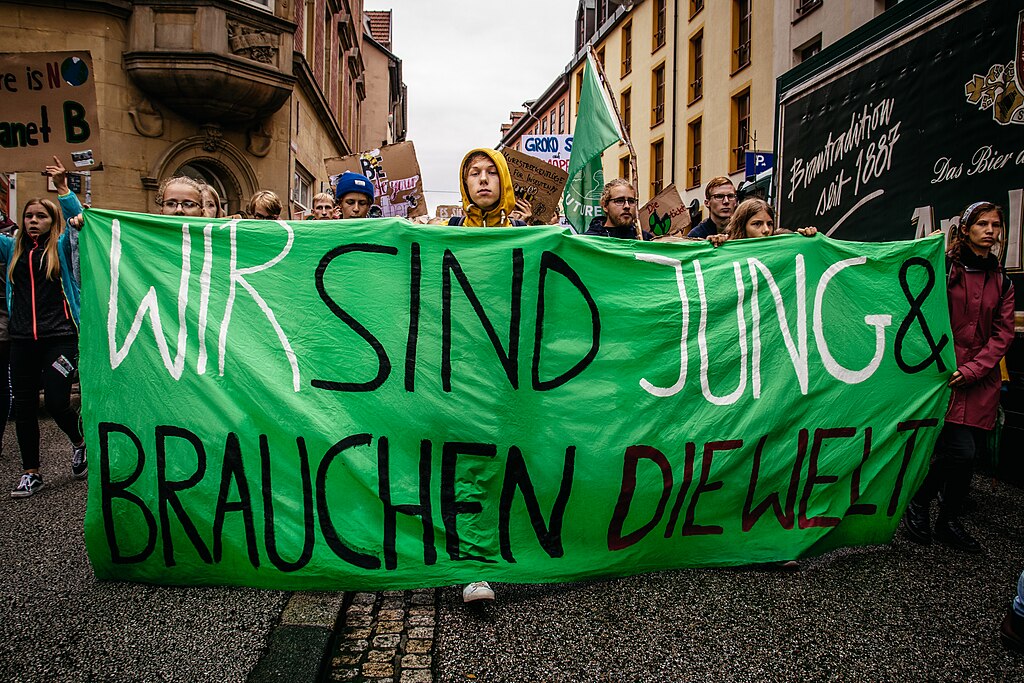 Menschen demonstrieren in der Stadt (Erfurt) und halten ein Banner mit der Aufschrift "Wir sind jung und Brauchen die Welt"